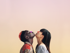 A dark skin boy with one  fair skin girl with long dark hair both chins touching and making contact. looking up. Both noses are colorful wearing spf reef safe sunscreen with a gradient background of light pink and yellow colors.
